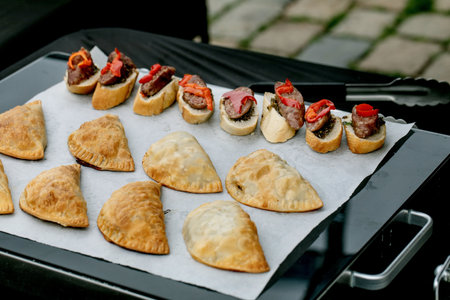 Delicious assortment appetizers: beef crostini topped with roasted peppers and golden baked...