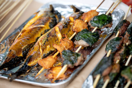 Traditional Japanese yakitori skewers with grilled fish and meat wrapped in shiso leaves on aluminum foil tray. Asian street food cuisine.の写真素材