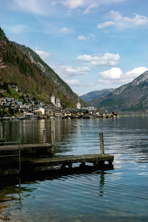 Beautiful Hallstatt alpine village view with wooden pier on lake mountain backdrop and church tower popular Austrian tourist destination in Alps.の写真素材