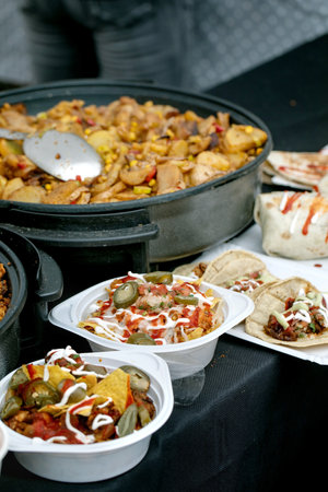 Mexican street food feast with chicken skillet corn tacos jalapenos. Containers filled with nachos meat vegetables topped with sour cream red sauce. Traditional Mexican cuisine.の写真素材