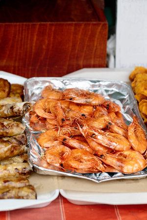 Grilled shrimp on aluminum foil tray served with other seafood dishes. Fresh cooked prawns ready for eating at seafood feast. Street foodの写真素材