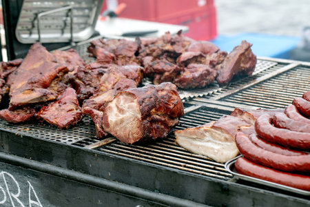 Juicy grilled meat chunks and sausages cooking on metal grill. Various cuts beef and pork barbecue. Outdoor cooking summer picnic concept.の写真素材