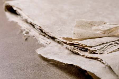 Closeup vintage mulberry paper sheets with torn edges textured surface natural beige color on...