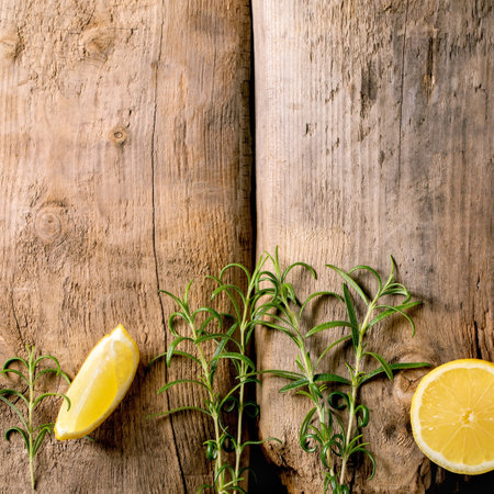 Citrus and herbs. Fresh organic sliced lemon and rosemary branches in row over old wooden background. Top view, copy spaceの写真素材