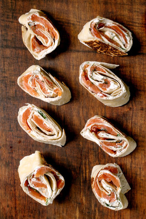 Delicious salmon pinwheels with cream cheese herbs on wooden background. Gourmet appetizers made with smoked salmon soft cheese filling wrapped tortilla.の写真素材