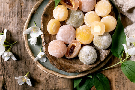 Top view colorful traditional Japanese mochi sweets arranged ceramic bowl wooden background white jasmine flowers decorative elementsの写真素材