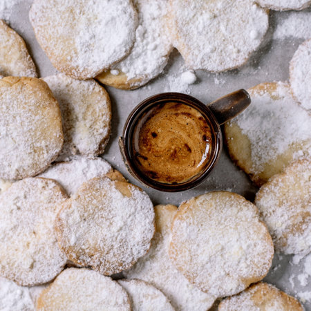 Homemade shortbread cookies dusted with powdered sugar. A true rustic dessert, homemade pastry. A cup of freshly brewed espresso on white baking paper. Top view.の写真素材