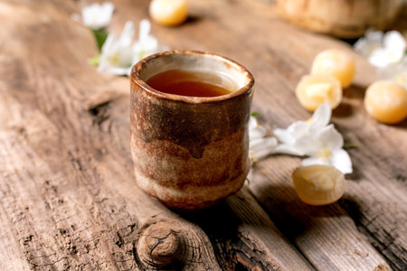 Ceramic cup herbal tea wooden table white flowers petals rustic natural setting healthy drink relaxation momentの写真素材