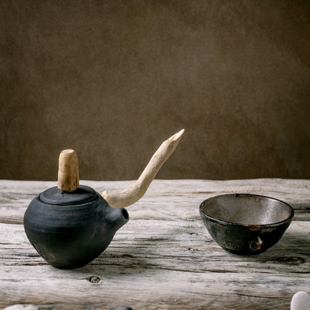 Original handmade ceramic teapot with wooden handle and cups for traditional Chinese tea drinking on an old wooden table. Decorative sea pebbles all around. Copy spaceの写真素材