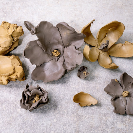 Creating Clay Flower: DIY ceramic Workshop Idea. Different spring clay flowers from dark and yellow clays, pieces of raw clay. Light background. Top view, bannerの写真素材