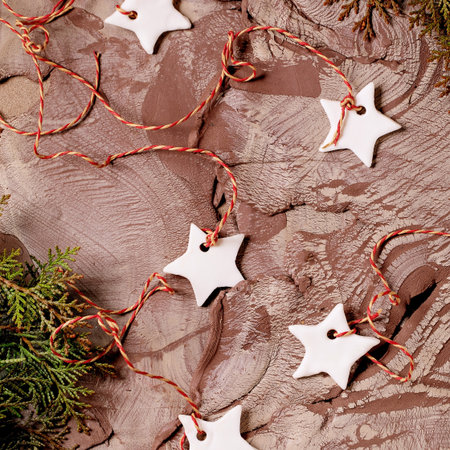 Christmas New Year background in the 2025 color of the year, Mocha Mousse. Christmas decorations white handcrafted porcelain stars, green branches on nerikomi-style raw clay mixture surface. Top view.の写真素材