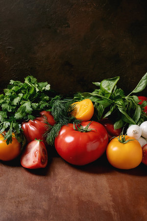 Fresh tomatoes herbs garlic arranged on dark rustic wooden surface. Healthy organic ingredients for cooking kitchen preparation concept.の写真素材