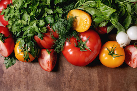 Fresh colorful vegetables herbs scattered on wooden table. Tomatoes peppers onions parsley basil dill arranged naturally. Healthy organic produceの写真素材