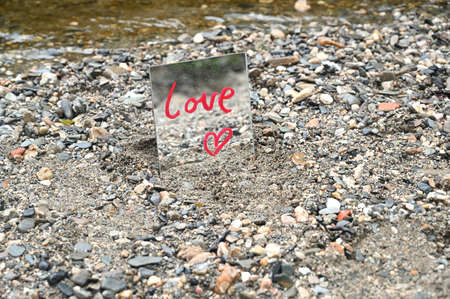 Love message written with red lipstick on a mirror in a natural environment