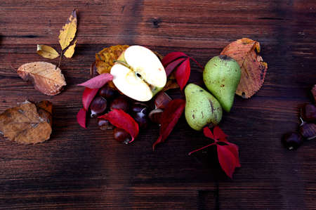 Autumn decor, leaves, apple, chestnut and pears on a wooden boardの写真素材