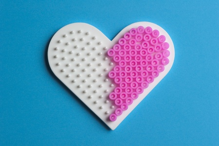 Making a heart with pink plastic beadsの写真素材