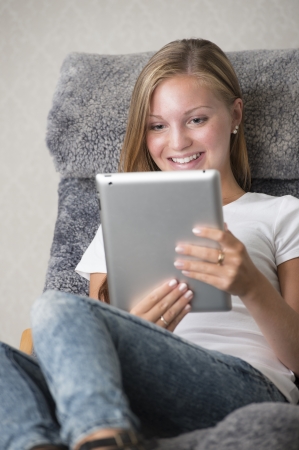 Beautiful girl relaxing at home, surfing the internet and looking at the screen of a touchpadの写真素材