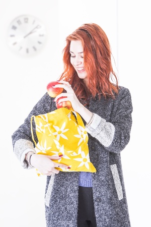 Cheerful young woman putting apples in reusable eco friendly shopping bagの写真素材