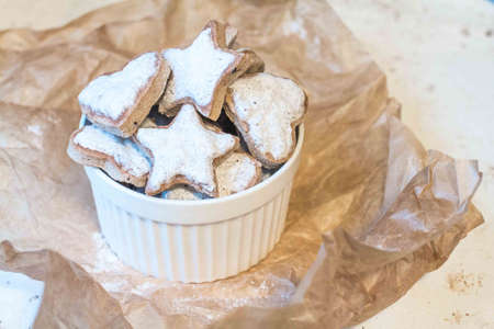 Photo of making Christmas cookies with icing in the form of stars, delicious gingerbread cookies on craft paper and decor in the form of snowflakes. Spicy cookies for New Year and Christmas with icing sugar.の写真素材
