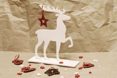 White deer with Christmas tree decorations on a craft background. Wooden deer decorated with New Year's toys.の写真素材