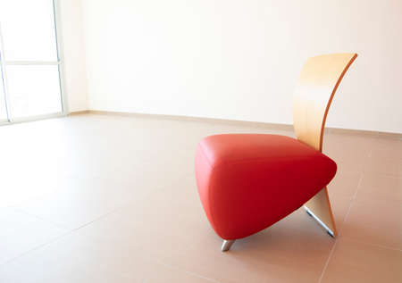 Design armchair with wood back and red leatherette seat in a corporate loungeの写真素材