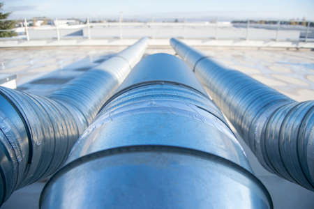 Air extractor and large galvanized steel pipes on the roof of a warehouse