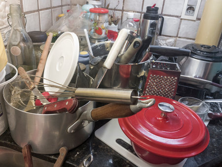 A very dirty, messy kitchen with lots of utensils to washの写真素材
