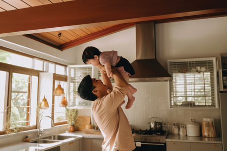 Asian father playing with his little daughter in the kitchen at home.の素材