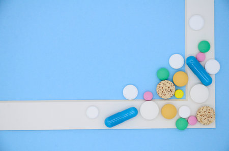 White frame and a lot of colorful medical pills, capsules on blue background with copy space.の写真素材