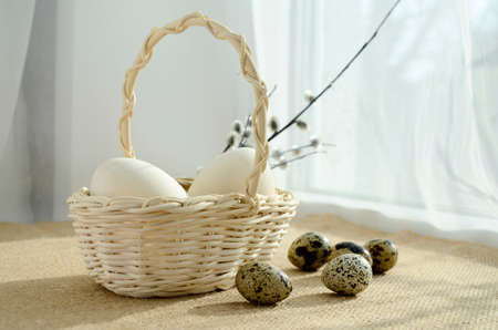 eggs in a white wicker basket and pussy willow branches on windowsill with copy space. Happy Easter concept, Easter table.の写真素材