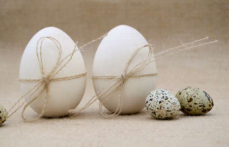 Two wooden eggs with twine bows, guail eggs on burlap background. The concept of Easter, birth.の写真素材