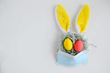 Easter bunny rabbit with yellow ears in medical mask on white background with copy space. Creative concept of Easter children's crafts.の写真素材
