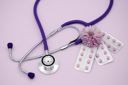 Stethoscope, three blisters with pink medical pills on pink background with copy space. Medical flat lay.の写真素材