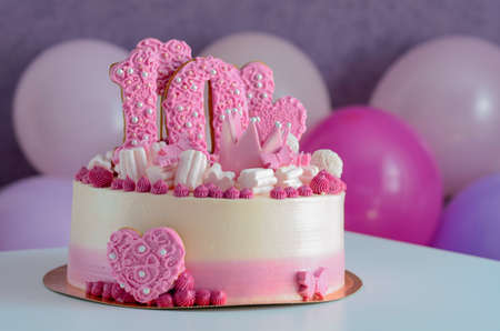 Pink and white cake with the number 10 and hearts on the table with balloons. Birthday.の写真素材
