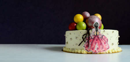 White cake with colorful balloons and girl standing with her back on table. Birthday, anniversary.