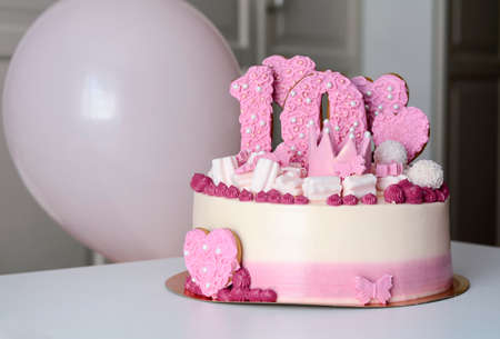 Pink and white cake with the number 10 and hearts on the table with balloons. Birthday.の写真素材