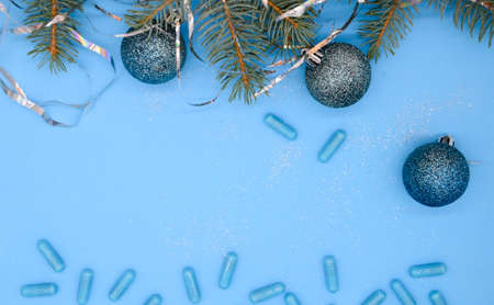 Blue medical capsules and a Christmas tree with a Christmas glitter balls on a blue background with copy space. Christmas medical flatly.の写真素材