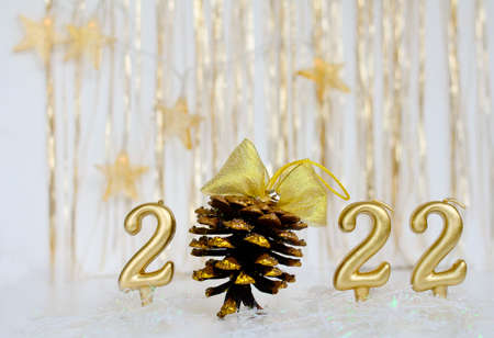 Number 2022 gold color and a cone with a golden bow. Concept of Christmas, new year.
