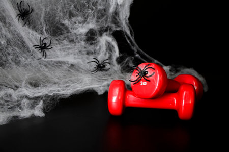 Two red dumbbells, spider web on black background with copy space. Concept of Halloween, sports.の写真素材