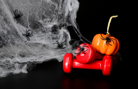 Two red dumbbells, spider web on black background with copy space. Concept of Halloween, sports.の写真素材