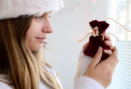 Child girl open small bags of gifts surprises advent calendar in her hands. Happy waiting Christmas and New Year.の写真素材
