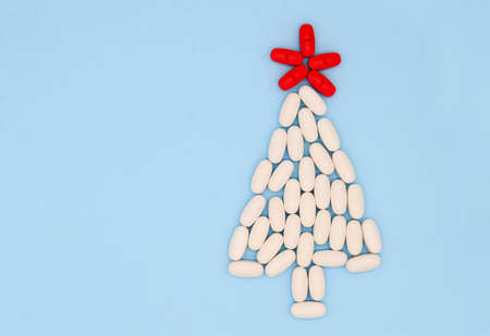 White red medical pills in form of Christmas tree on blue background. Christmas medical flatly.の写真素材
