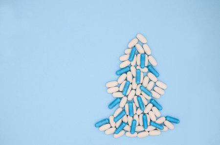 White red medical pills in form of Christmas tree on blue background. Christmas medical flatly.