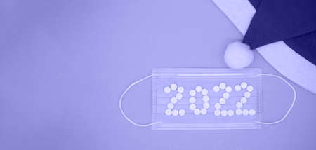 Medical pills in form of number 2022 on medical face mask and Santa hat in color of year 2022. Christmas medical flatly.の写真素材