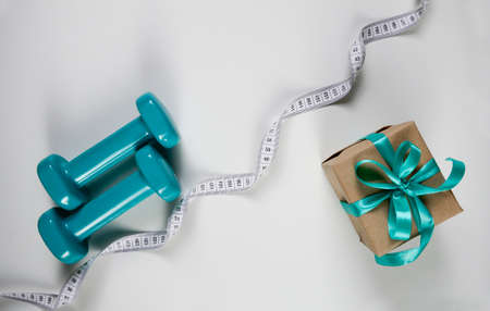 Two sports dumbbells and white measuring tape on white background with copy space, Christmas sport flatlay. Home training, gift.の写真素材