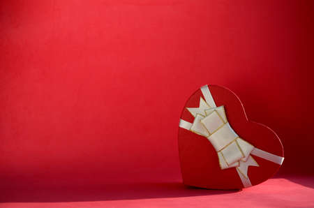 Gift box in shape of heart with bow on red background with copy space. Gift for Valentine's Day, March 8, mother's day, birthday.の写真素材