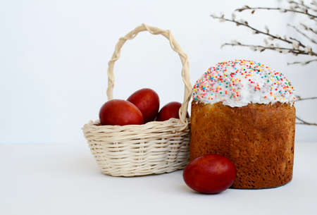 Easter cake, painted eggs in basket, willow branches on white background with copy space.の写真素材