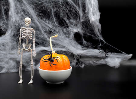Skeleton, spider web, pumpkin on black background with copy space. Concept of scary Halloween.の写真素材