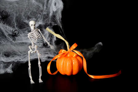 Skeleton, spider web, pumpkin on black background with copy space. Concept of scary Halloween.の写真素材