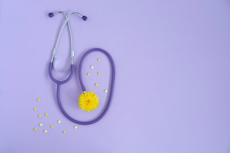 Stethoscope and yellow flower , yellow pills on lilac background with copy space. Medical flat lay. world pharmacist's dayの写真素材